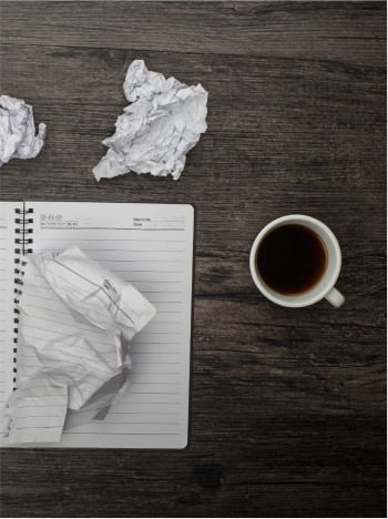 Secret&aacute;ria com pap&eacute;is amarrotados, um caderno e uma ch&aacute;vena de caf&eacute;
